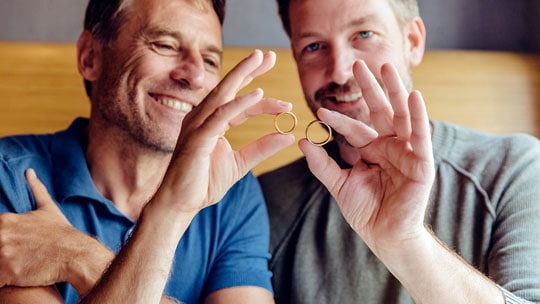 Two men admire their wedding bands.